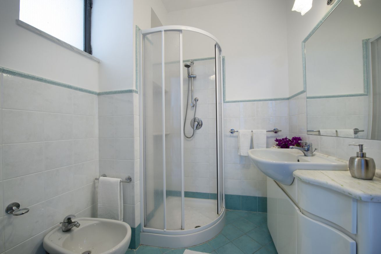 Een badkamer met een douche, wastafel en toilet.