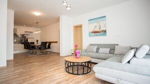 Una sala de estar moderna con un sofá gris, una mesa de centro de madera y un comedor con una mesa y sillas.