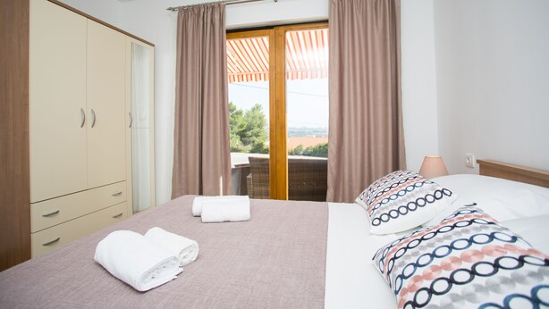 Habitación de hotel con cama, armario, ventana con cortinas y vistas al exterior.