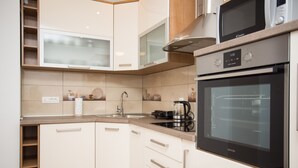 Una cocina moderna con armarios blancos, un horno de acero inoxidable y un microondas.