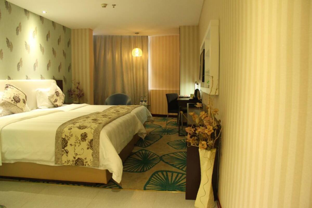 A hotel room with a bed, a desk, and a chair.