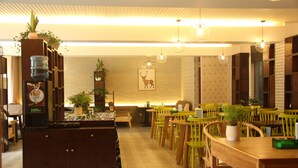 Ein Restaurant mit Holztischen und -stühlen, einem Wasserspender und Topfpflanzen.