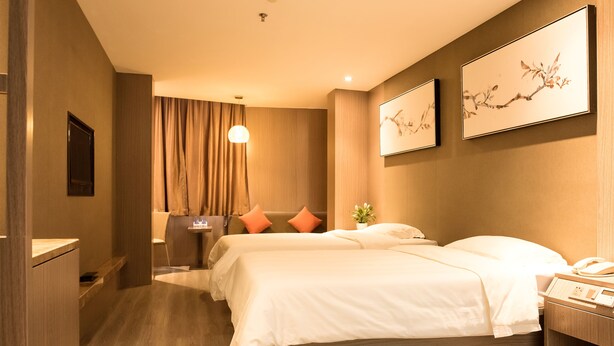Ein Hotelzimmer mit zwei Betten, einem Nachttisch, einer Lampe und einem Bild an der Wand.