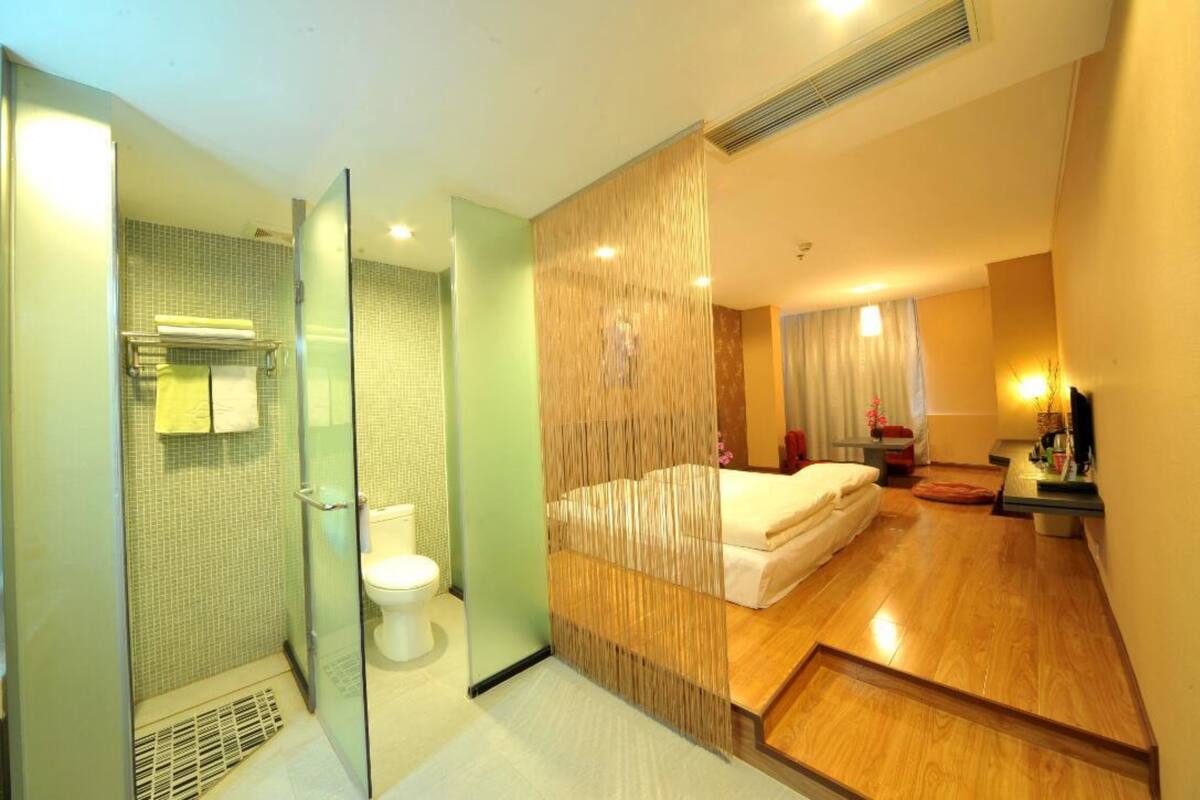 A modern bathroom with a glass shower enclosure, a toilet, and a wooden floor.