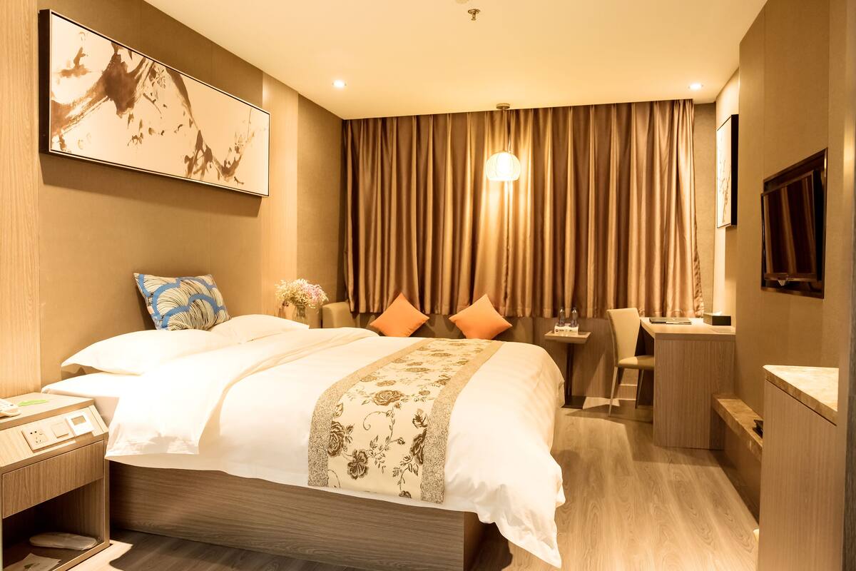 A hotel room with a large bed, a desk, and a chair.