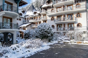 A multi-story hotel with balconies, snow-covered trees, and a paved driveway.