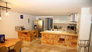Eine moderne Küche mit einer Holztischinsel, eingebauten Geräten und einem Essbereich mit Tisch und Stühlen.