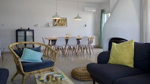 A living room with a sofa, a wicker chair, a dining table with chairs, and pendant lights. - NEW! Luxury 8 bed villa with magnificent roof terrace, 100m from the sea. (Chloraka)