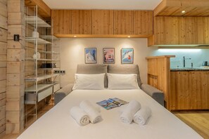 Ein Hotelzimmer mit einem Bett, einer Holzwand, einer Metallregaleinheit und einer kleinen Küchenzeile.
