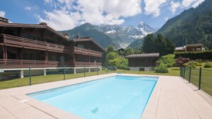 Ein Schwimmbad mit Blick auf eine Berglandschaft, umgeben von Gebäuden mit Balkonen.