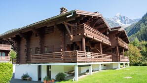 Eine Holzhütte mit Balkon vor einer Bergkulisse.