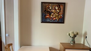Ein Essbereich mit Tisch und Stühlen, einer kleinen Kommode und einem Bild an der Wand.