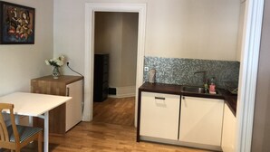 Eine kompakte Küche mit Esstisch aus Holz, einem kleinen Schrank und einer gefliesten Spritzschutzwand.