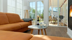 Een moderne woonkamer met een bank, een klein rond tafeltje met drinkgerei en een open haard.