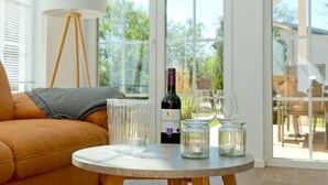 Een kamer met een ronde tafel, een bank, een lamp en een fles wijn.