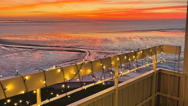 A balcony with a view of a sunset over a body of water. - Apartment with a dream view directly on the Pearl Bay (Büsum)