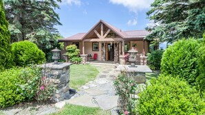 Une maison avec un chemin de pierre menant à l’entrée, entourée d’une végétation luxuriante et d’arbres.