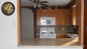 A compact kitchen with a microwave, stove, and wooden cabinets. - Cozy country bungalow within the Amish Community (Leacock-Leola-Bareville)