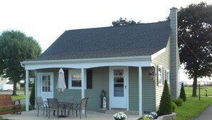 A small, single-story house with a porch, a table and chairs, and a potted plant. - Cozy country bungalow within the Amish Community (Leacock-Leola-Bareville)