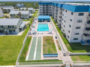 A multi-story hotel with a rooftop pool, outdoor seating, and a tennis court. - 🏖️Top Floor Ocean View Retreat with Balcony and Pool, Close to Shopping and Dining | HA508🌊 (New Smyrna Beach)