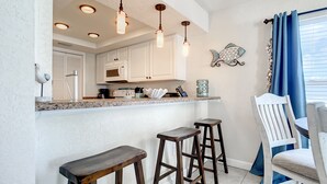 Eine Küche mit weißen Schränken, einer Granit-Arbeitsplatte und drei Holz-Barhocker.
