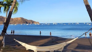 Ein Strand mit Palmen, einer Hängematte und Spaziergängern.