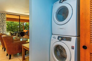 A stacked washer and dryer unit with a control panel, located in a room with a dining area and large windows.