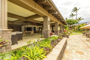 Un patio al aire libre con paredes de piedra, muebles de mimbre y diversas plantas.