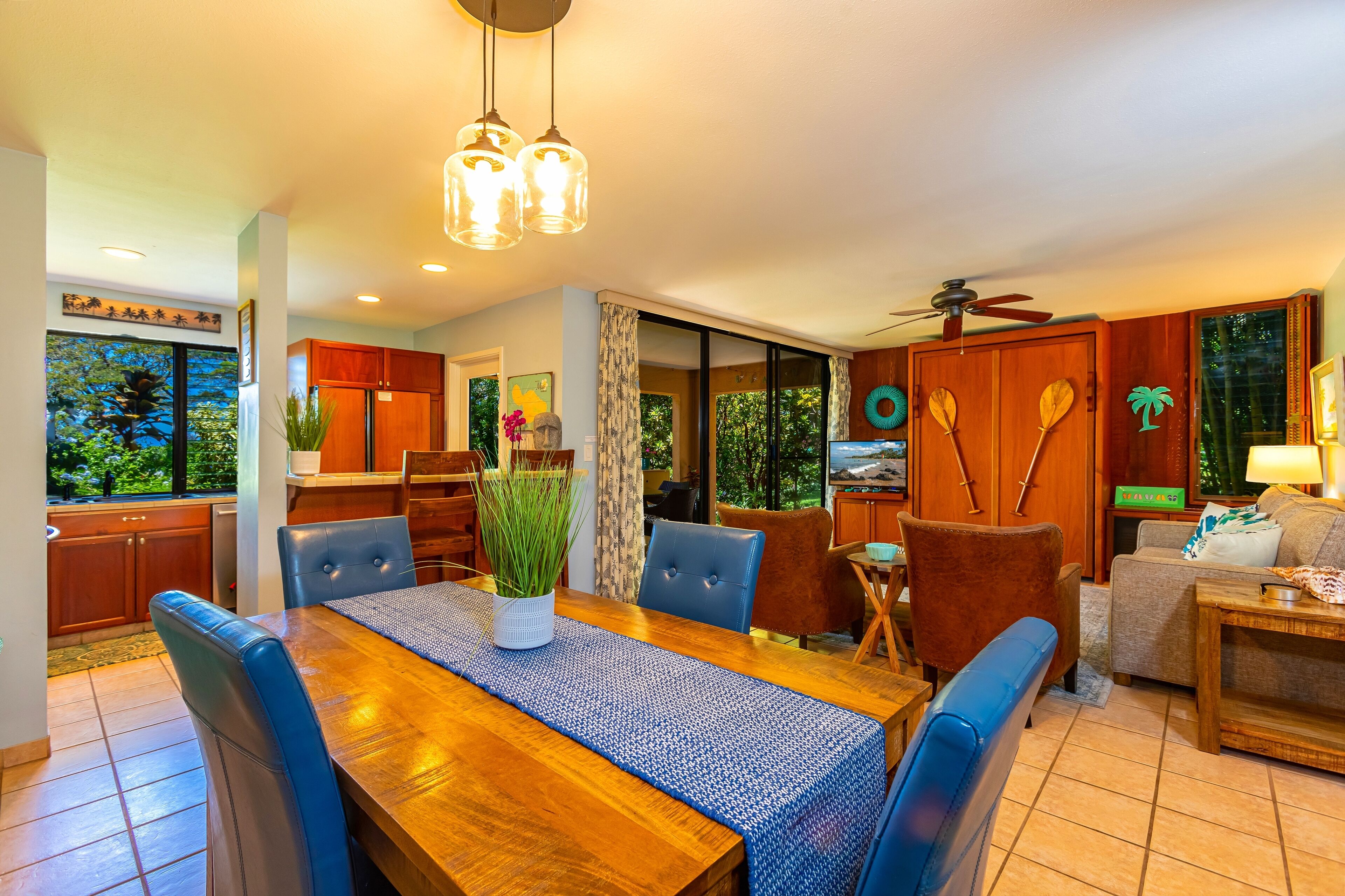 Una cocina moderna con armarios de madera, una mesa de comedor con sillas azules y un ventilador de techo.