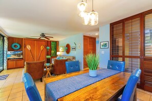 Un comedor con mesa de madera, sillas tapizadas en azul y un ventilador de techo.