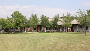 A building with multiple rooms, a grassy lawn, and trees. - Private 36-Acre Ranch Near Austin & Dripping Springs - Pond & Fire Pit (Driftwood)