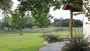 A well-maintained grassy area with a concrete pathway leading to a wooden structure. - Private 36-Acre Ranch Near Austin & Dripping Springs - Pond & Fire Pit (Driftwood)