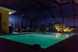 A swimming pool with a covered area, chairs, and a view of the outdoors at night. - Perfect getaway - Canal front, close to the beach (Rotonda West)