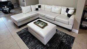 Een moderne woonkamer met een hoekbank, een salontafel en een decoratief wandkunstwerk.