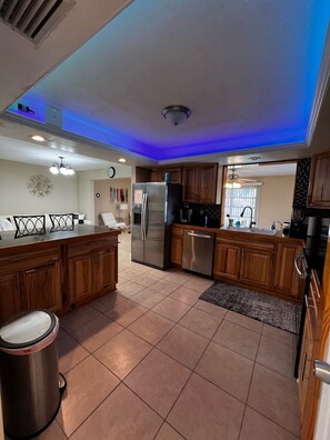 Kitchen features a central island with a sink and refrigerator, stainless steel appliances, and recessed lighting.