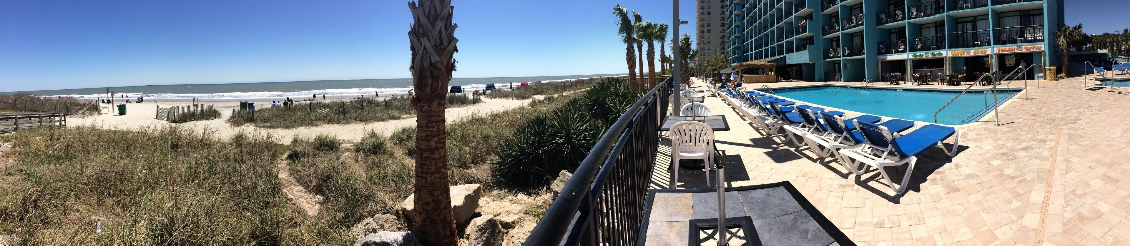 A beachside hotel with a pool, beach access, and a view of the ocean.
