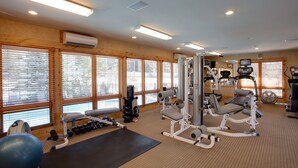 Une salle de sport équipée de matériel d’exercice, dotée de grandes fenêtres et d’un ventilateur de plafond.