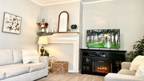Uma sala de estar com lareira, televisão, sofá e um espelho decorativo.