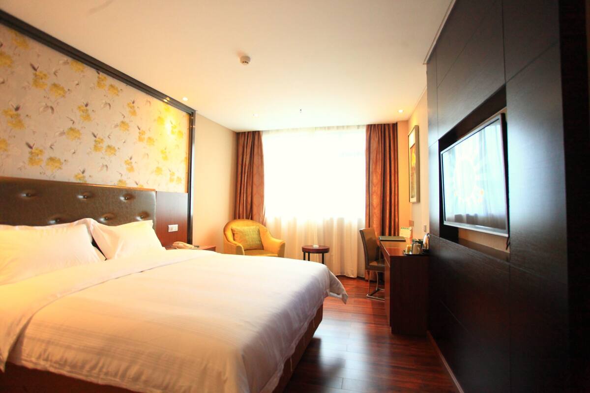 Habitación de hotel con una cama grande, una silla, un escritorio y una ventana con cortinas.