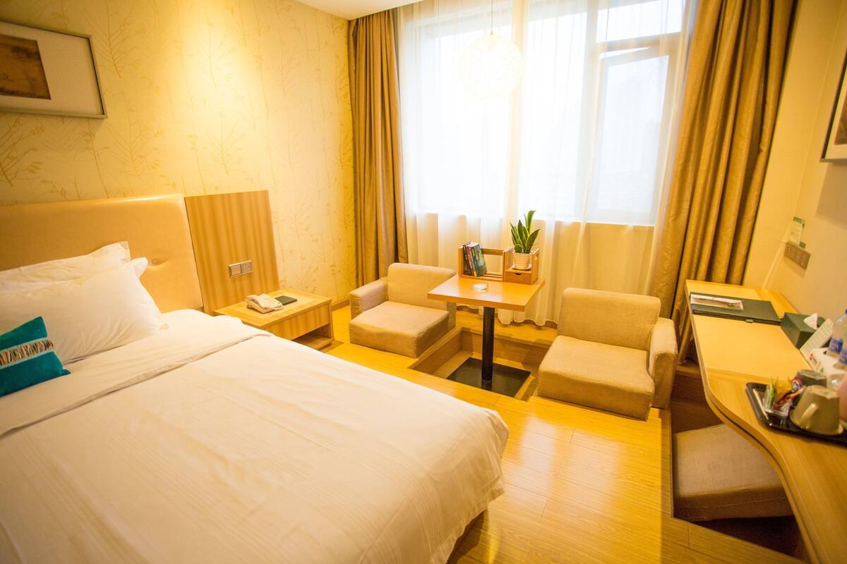 Habitación de hotel con una cama grande, un escritorio, una silla y una mesita con una planta.