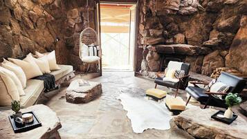 Un intérieur chaleureux avec un mur en pierre, un fauteuil suspendu, un canapé et une cheminée.