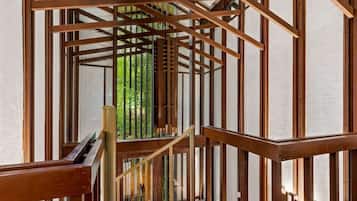 Una escalera de madera con barandilla de metal que lleva a un vidrio con vista a la vegetación.