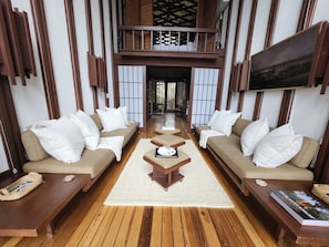 A spacious living area with two sofas, a coffee table, and a TV mounted on the wall.