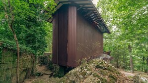 Une structure en bois dotée d’un toit en pente, entourée d’une végétation luxuriante.
