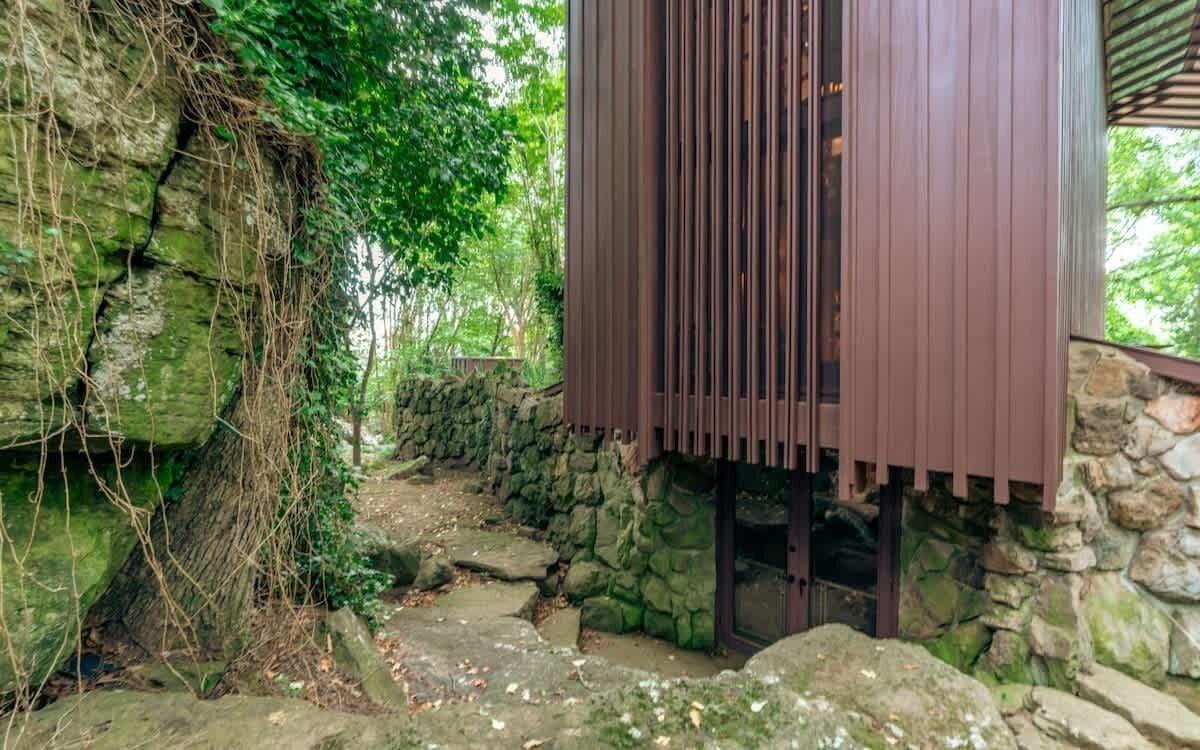 A stone-walled building with a wooden structure on top, surrounded by greenery.