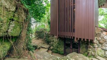 A stone-walled building with a wooden structure on top, surrounded by greenery.