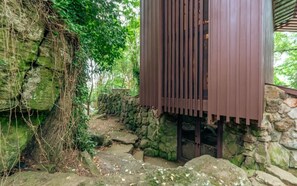 A stone-walled building with a wooden structure on top, surrounded by greenery.