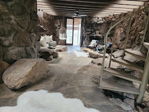 A stone-walled room with a staircase, a sofa, and a chair.