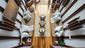 A compact, modern room with a central wooden divider, two sofas with cushions, a small table, and a clock.