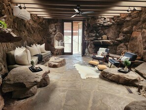 A rustic interior with a stone wall, a sofa, a chair, and a fireplace.